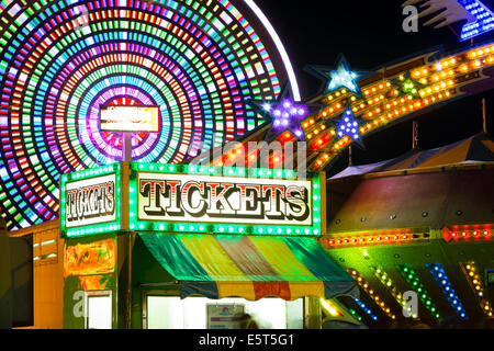 Carnival rides spin in the night blurring their lights in Wasaga Beach as people enjoy the midway during a warm summer night. Stock Photo