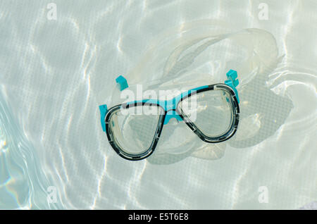 Diving mask or goggles floating in swimming pool. Stock Photo