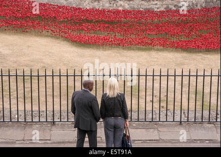 London, UK, 5 August 2014.  In the dry moat of the Tower of London, the evolving art installation called 'Blood Swept Lands and Seas of Red', by ceramic artist Paul Cummins, was unveiled to the public to recognise 100 years since the first full day of Britain’s involvement in the First World War.  Pictured :   Pictured : a couple view the poppies in the dry moat.  Credit:  Stephen Chung/Alamy Live News Stock Photo
