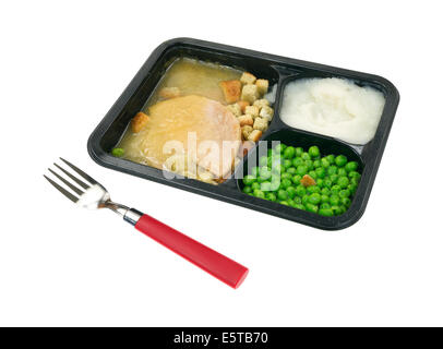 A sliced turkey in gravy with mashed potatoes and green peas TV dinner in black tray with red handled fork in the foreground. Stock Photo