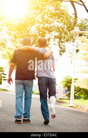 friend helping brothers or patient  to walk on the road Stock Photo