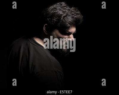 License available at MaximImages.com - Dramatic portrait of an angry middle aged man isolated on black background Stock Photo