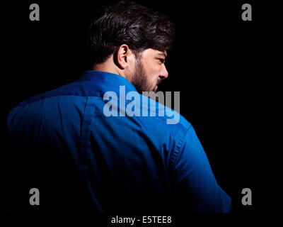 Portrait of an angry middle aged man looking over his shoulder isolated on black background Stock Photo