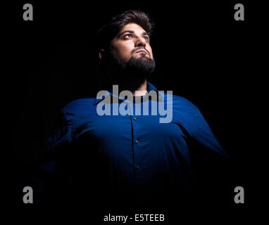 License available at MaximImages.com - Dramatic portrait of a Middle eastern man looking up at the light isolated on black background Stock Photo