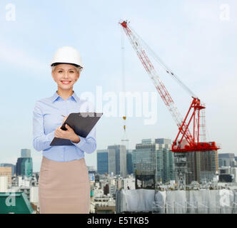 smiling businesswoman in helmet with clipboard Stock Photo