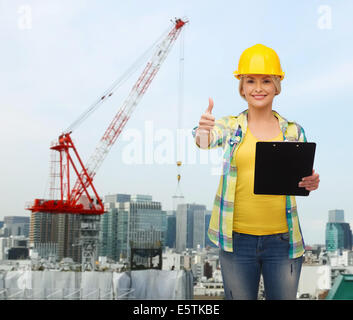 smiling woman in helmet with clipboard Stock Photo