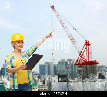 smiling woman in helmet with clipboard Stock Photo