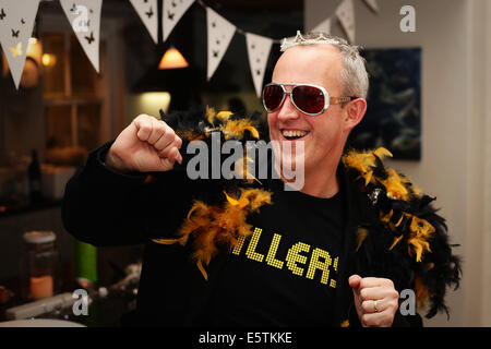 A forty five year old man in a Killers T shirt and feather boas dancing Stock Photo