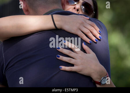 A woman with blue painted nails holds on tight to her partner in a public street. Stock Photo