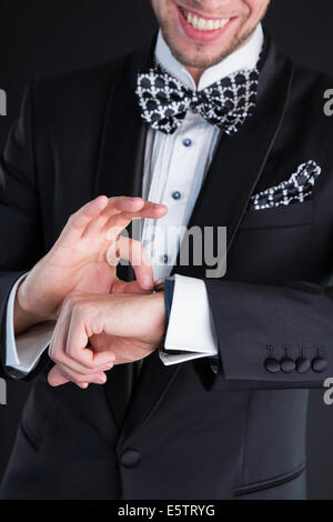 Man in a tuxedo winds up watches Stock Photo