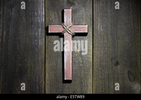Spotlight on wood cross hanging on rustic wooden background Stock Photo