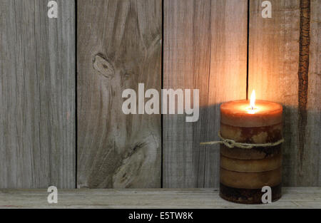 Textured burning candle by rustic wooden background Stock Photo