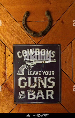 'Cowboys leave your guns at the bar' says a sign at La Reata Ranch near Kyle, Saskatchewan, Canada. Stock Photo