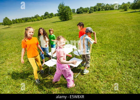 Children go around playing musical chairs outside Stock Photo