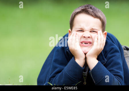 boy outdoors without upper two teeth with pain in the face Stock Photo
