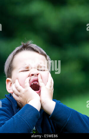 boy outdoors without upper two teeth with pain in the face Stock Photo