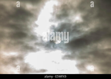 Sun behind dark clouds Stock Photo