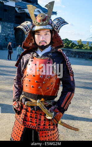 Japanese man wearing traditional samurai armour / armor, including helmet and swords Stock Photo