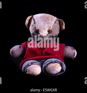 Studio shot of old well loved soft toy. 1970's vintage, well worn, repaired and wearing clothes. Stock Photo