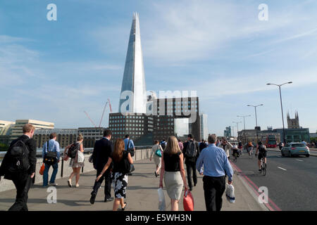 City of London office workers  crossing London Bridge at rush hour after work in summer with a view of the Shard skyscraper London UK   KATHY DEWITT Stock Photo