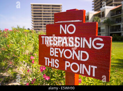 No trespassing sign in front of flower gardens next to private apartments by beach in Florida, USA Stock Photo