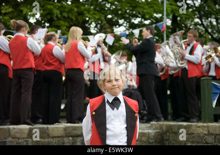 A girl mascot and a Brass Band play at the Oldham and Saddleworth Whit Friday Brass Band Contest, Lancashire, UK at dusk Stock Photo