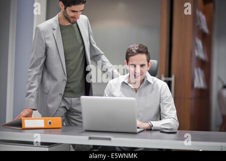 Two men in office, one using laptop Stock Photo