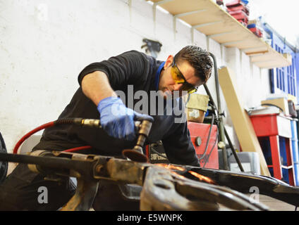 Mechanic cutting engine part with grinder Stock Photo