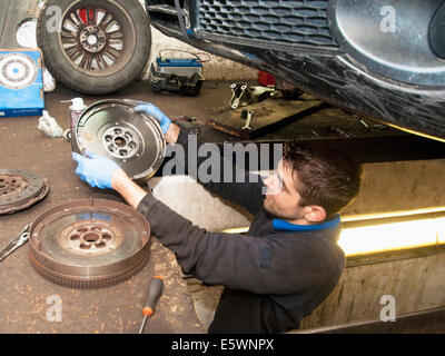 Mechanic checking disc of wheel underneath car Stock Photo