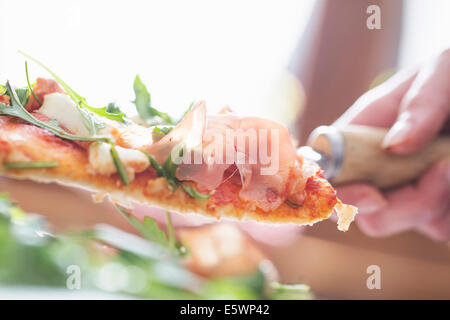 Cropped close up of female hand with pizza slice on spatula Stock Photo