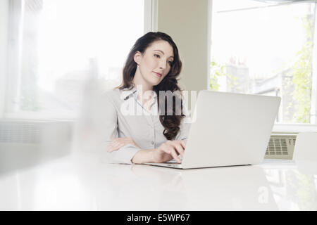 Young businesswoman using laptop in office Stock Photo