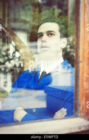 Portrait of young man in vintage jacket gazing through window Stock Photo