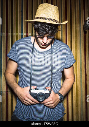 Portrait of young man looking down at vintage camera Stock Photo