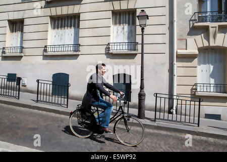 Mid adult man cycling down cobbled city street Stock Photo