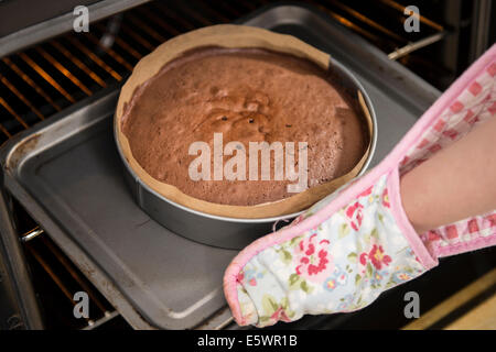 Close up of female hands removing cake from oven in bakery Stock Photo