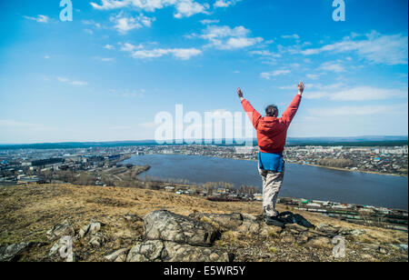 Rear view of young female hiker celebrating on top of mountain Stock Photo