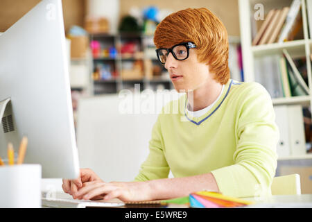 Smart guy sitting at workplace and working with computer Stock Photo