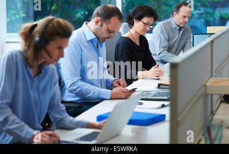 Businesspeople sitting at desk working Stock Photo