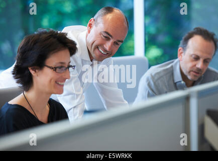 Colleagues sitting at desk, smiling Stock Photo