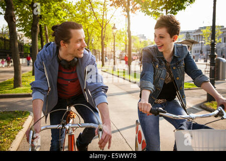 Young adult couple cycling through city, Vienna, Austria Stock Photo