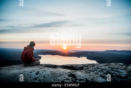 Young female hiker gazing at sunset over distant lake