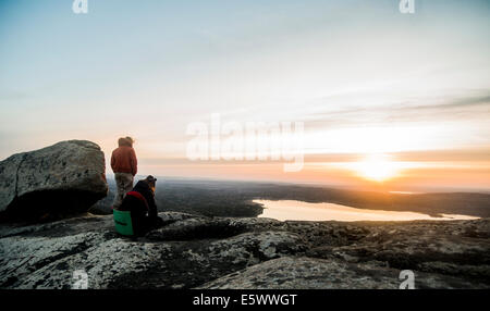 Two young female hikers gazing at sunset over distant lake
