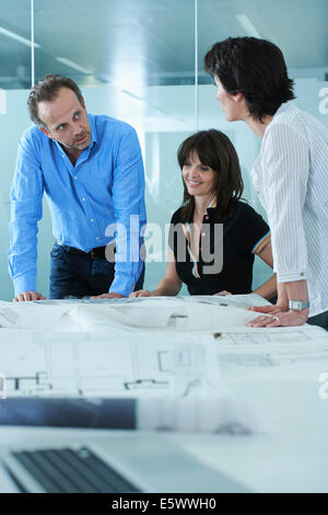 Architect showing client blueprints on boardroom table Stock Photo