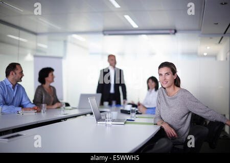 Portrait of businesswoman with colleagues at boardroom table Stock Photo