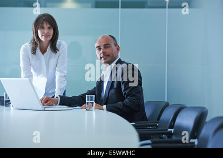 Portrait of businesswoman and man at boardroom table Stock Photo