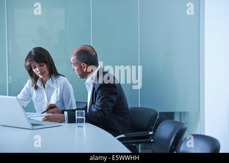 Businesswoman and man doing paperwork at boardroom table Stock Photo