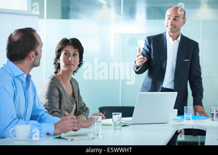 Businessmen and women arguing across boardroom table Stock Photo