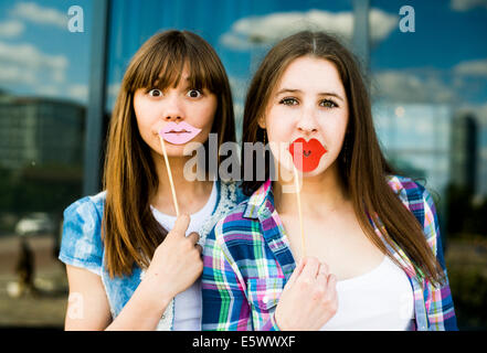 Portrait of two young women holding up lip costume masks