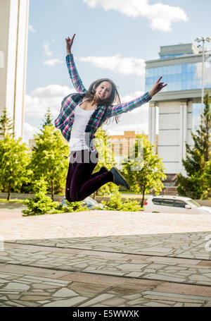 Young woman jumping mid air in city Stock Photo