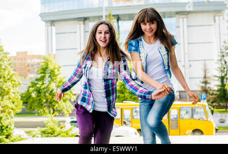 Two young women holding hands and running in city Stock Photo